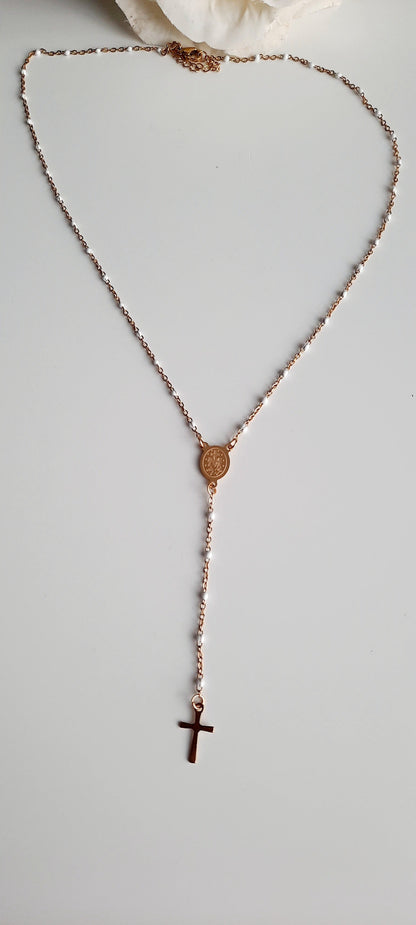 Collier doré en acier inoxydable. Chaine fine incrustée de perles blanches. Sautoir en Y, avec en son centre une médaille gravée, les deux faces sont différentes. Le collier se termine par une fine croix dorée. On adore la finesse de ce bijoux finement travaillé, facile à accorder avec d'autres bijoux. Se porte en soirée ou lors d'évènements moins formels. Absolument tendance. Se décline en bracelet. Dans le même style