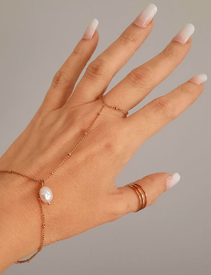 Bracelet de main en acier inoxydable doré ou argenté  Chaine fine à billes qui embellit la main sur laquelle il se glisse avec finesse. Bijoux ornée d'une perle d'eau douce  Terriblement chic, tendance et féminin, on craque pour ce bijoux qui vous accompagnera pour toutes occasions ! Peu de porter à différents doigts en fonction de vos gouts Dimensions : diamètre de l'anneau 1.8cm, longueur de la chaine dessus main 7cm, longueur de la chaine poignet 15+5cm environ. Fermoir en pince de homard